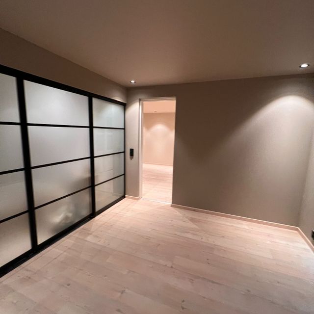 Moderne lysebrunt rom med garderobeskap med gjennomsiktig frostet glass